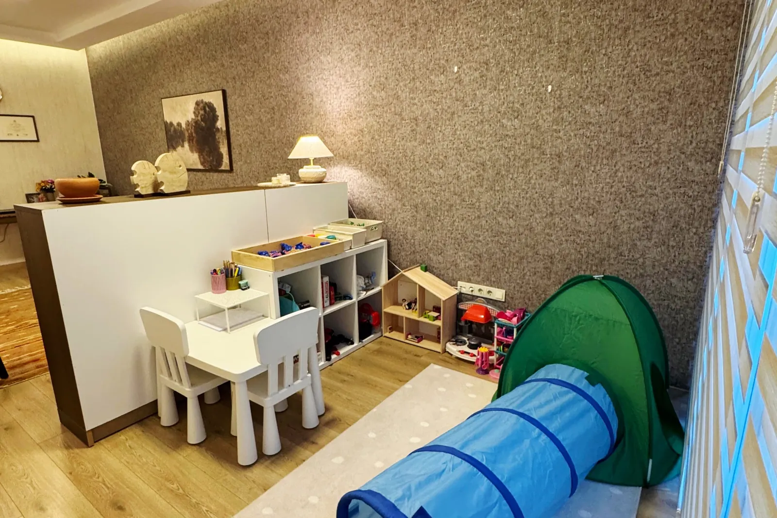 Oyun terapisi alanı: çocuk masası, oyuncak rafları, bebek evi ve oyun çadırı